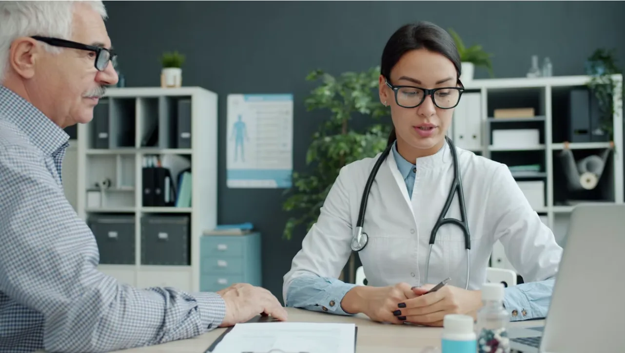 A clinician going over a document at a desk with an older patient.